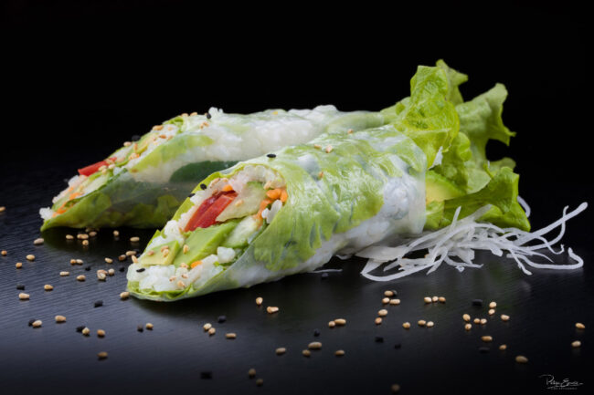 Shooting culinaire pour le restaurant An Sushi 9 Deux longs rouleaux de printemps sur une table noire avec des graines de sésame autour