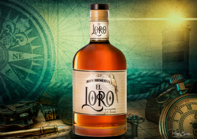 Bouteille de rhum de couleur ambré, posée sur une carte marine ancienne avec un perroquet sur l’étiquette de la bouteille.