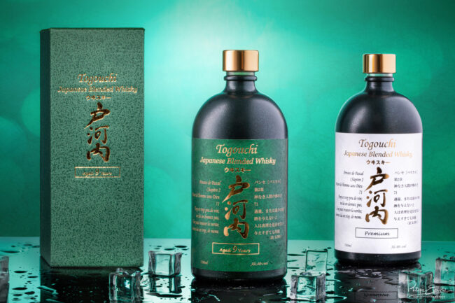 Shooting de bouteilles avec mise en scène pour la Société RF Distribution 6 Deux Bouteilles de whisky japonais posées sur un fond noir avec des glaçons et des gouttes d’eau autour.