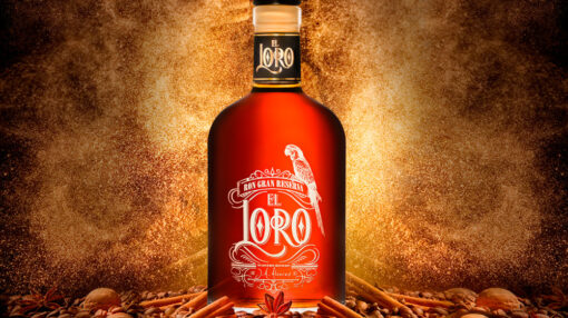 Une Bouteille de rhum est posée sur un monticule composé de noix, de bâtons de cannelle et grain de café.