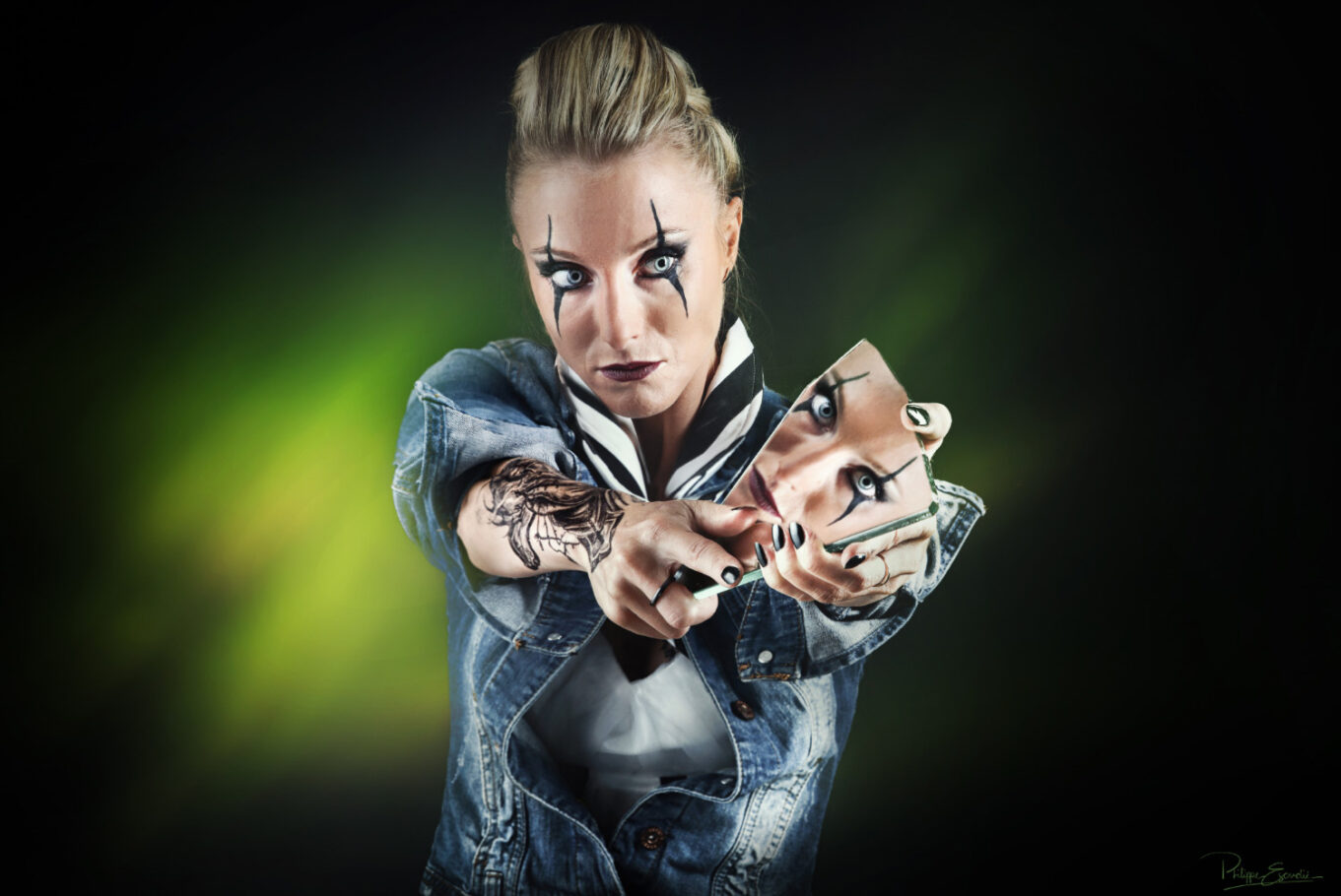 Une femme blonde tient un miroir sur lequel est incrusté le reflet de son visage