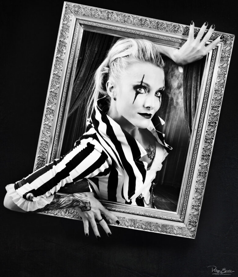 Une femme tient un cadre de tableau à la main et semble sortir du cadre