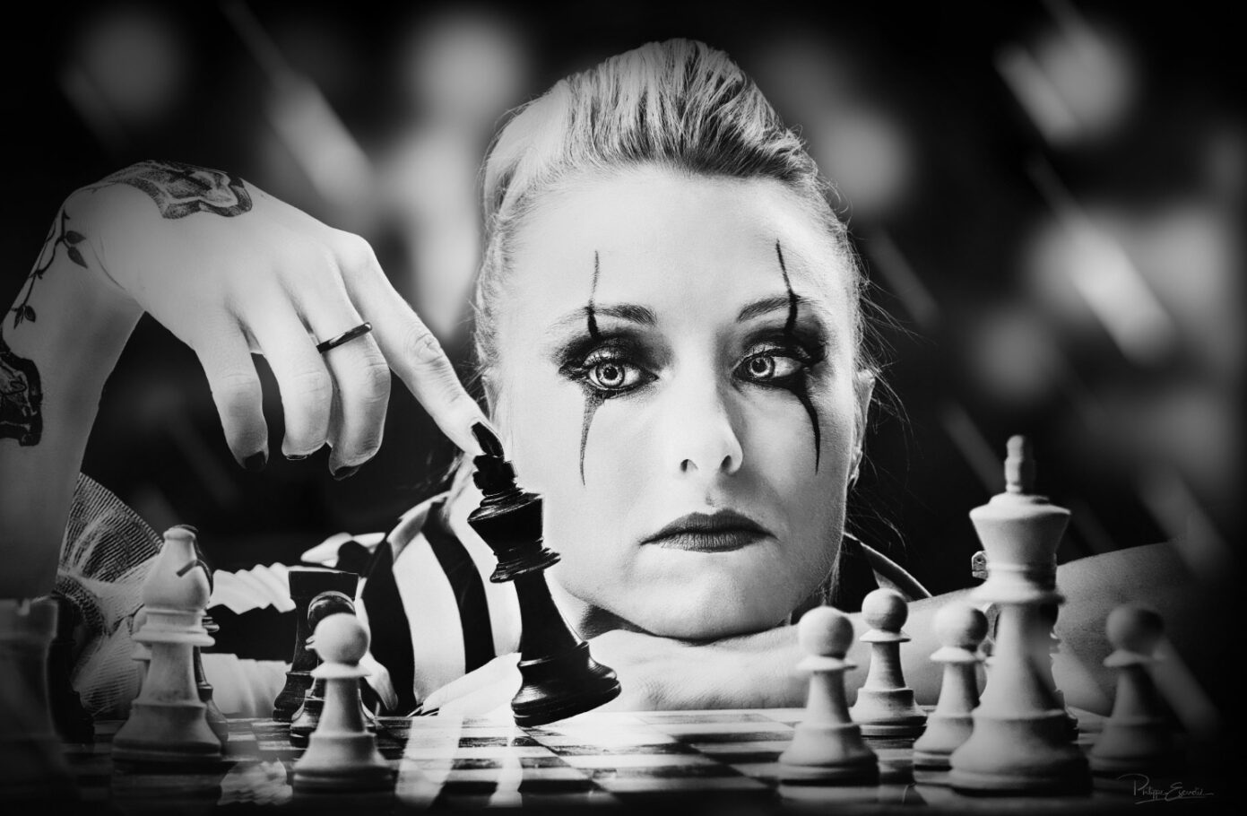 Derrière un échiquier la joueuse incline de son doigt le roi noir