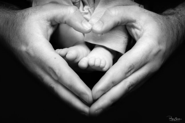 Séance photo nouveau-né et parents 3 Deux mains forment un cœur au-dessus de deux pieds dun bébé