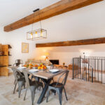 Salon de cuisine avec une table dressée et un plafond à poutre bois apparente