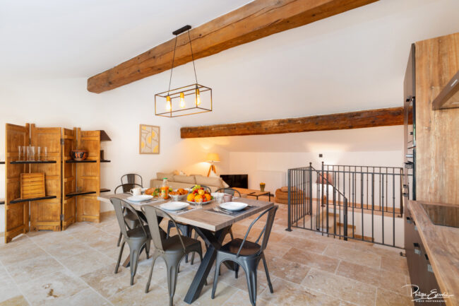 Shooting immobilier, pour maisons d’hôtes, gîtes, hôtels, propriétaires ou conciergerie. 2 Salon de cuisine avec une table dressée et un plafond à poutre bois apparente