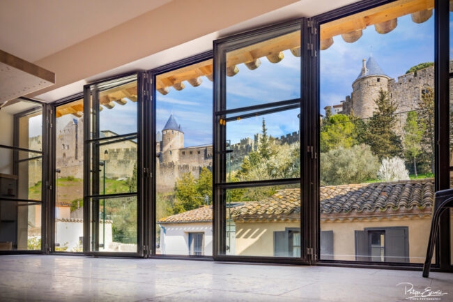 Shooting immobilier, pour maisons d’hôtes, gîtes, hôtels, propriétaires ou conciergerie. 3 Vaste baie vitrée avec la Cité de Carcassonne en arrière plan.