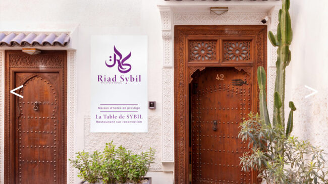 Entrée d'un riad avec un panneau marqué Riad Sybil et deux portes en bois