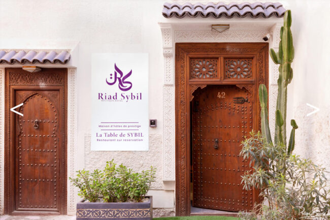 Entrée d'un riad avec un panneau marqué Riad Sybil et deux portes en bois