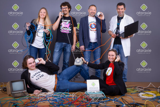 Un groupe de personnes posant pour une photo, chacune tenant un câble un téléphone ou un ordinateur