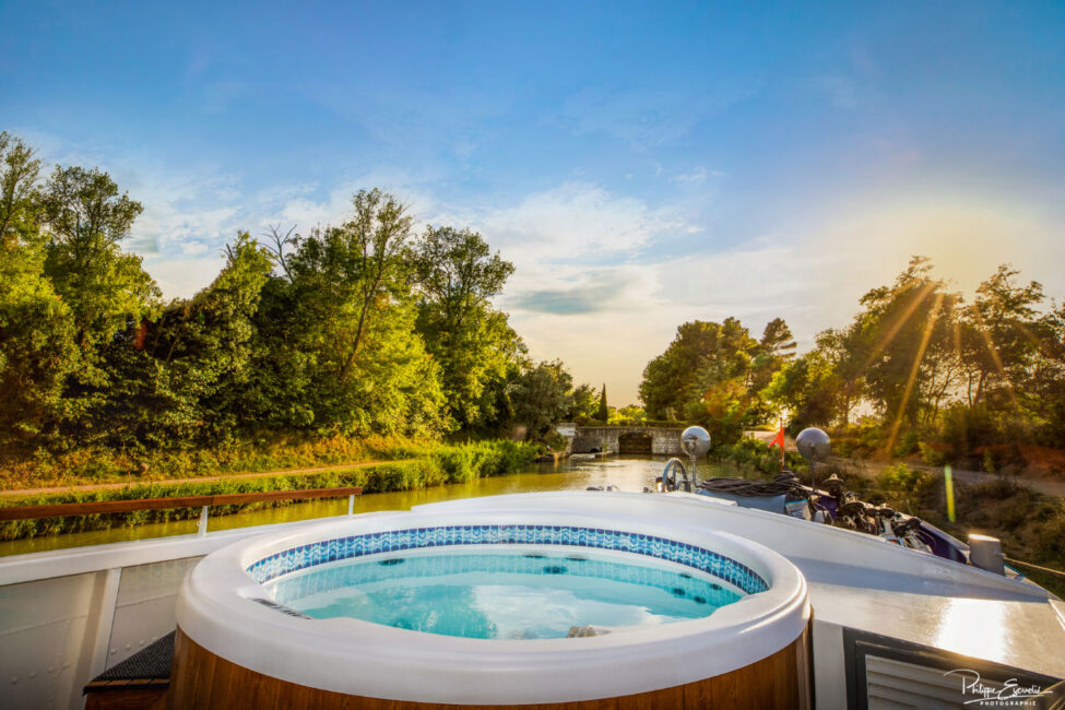 Un jaccuzzi sur le pont avant d'une péniche sur les eaux du canal du midi en fin de journée