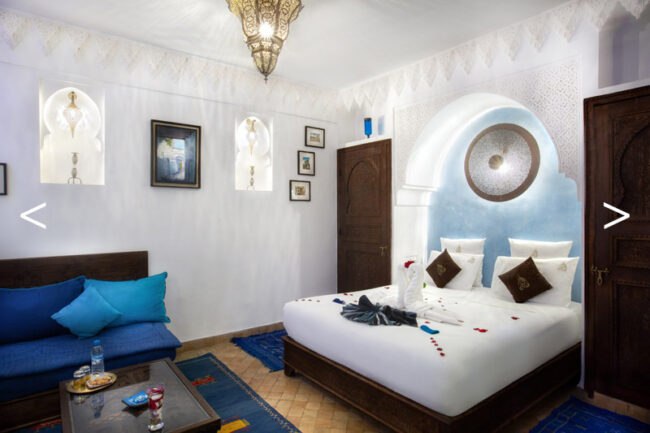 Intérieur cosy d'une chambre de riad comprenant un lit, un canapé, une table et une lampe