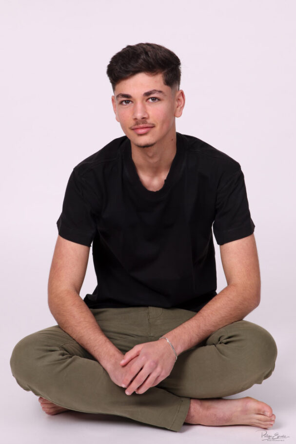 portrait d'un Jeune homme assis en tailleur sur fond blanc