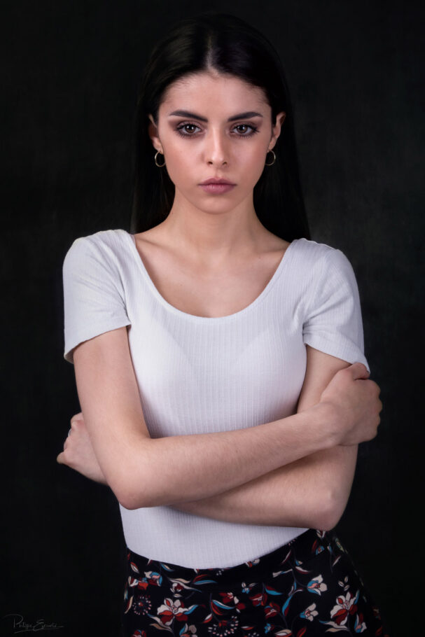photo pour agence d'une fille aux long cheveux longs sur fond sombre les bras croisés