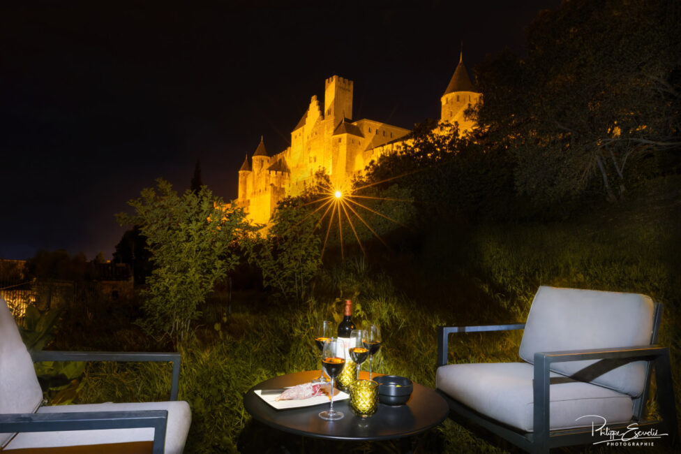 Deux chaises et une table avec du vin et de la nourriture devant un château majestueux.
