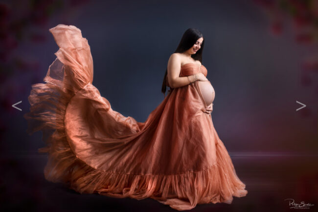 Femme enceinte de profil portant une longue robe ocre, au sourire radieux