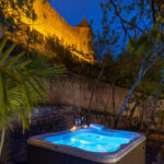 jacuzzi éclairé de nuit dans un jardin avec en arrière plan les murailles de la Cité de Carcassonne