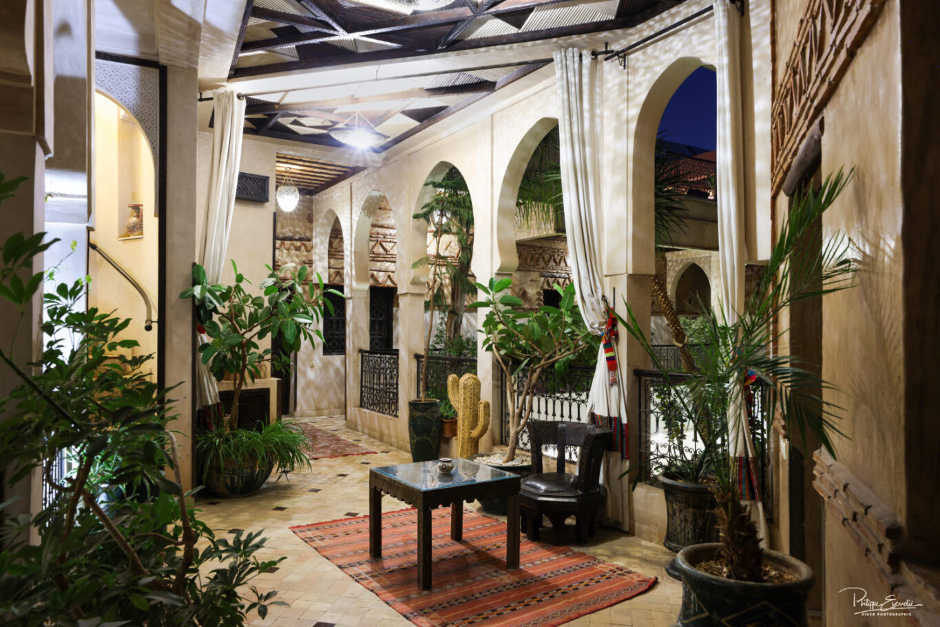 coursive de riad de nuit avec des tentures et de la végétation