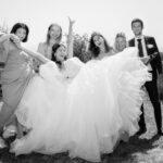 Photo en noir et blanc d'un groupe de mariage, ambiance festive avec la mariée tenue en l'air par ses témoins