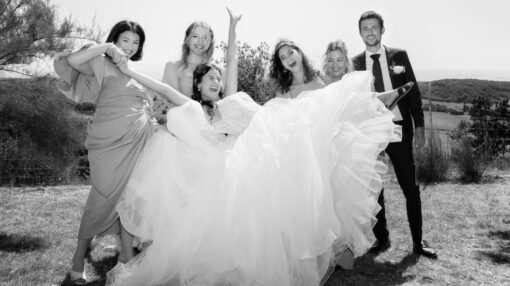 Photo en noir et blanc d'un groupe de mariage, ambiance festive avec la mariée tenue en l'air par ses témoins
