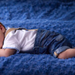 bébé souriant allongé sur une couverture bleue atmosphère douce