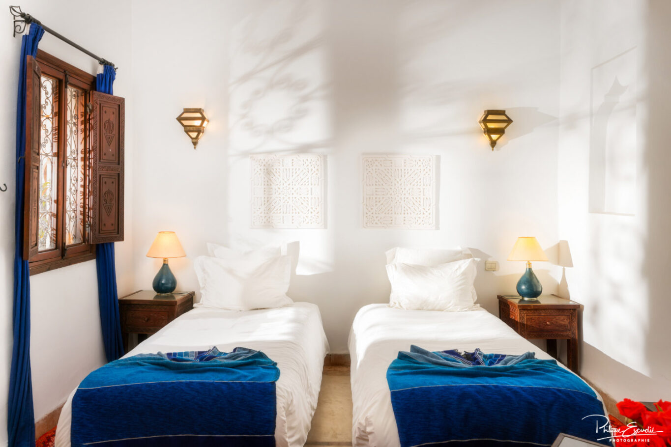 chambre de riad avec lit double aux draps blancs et couvertures bleues