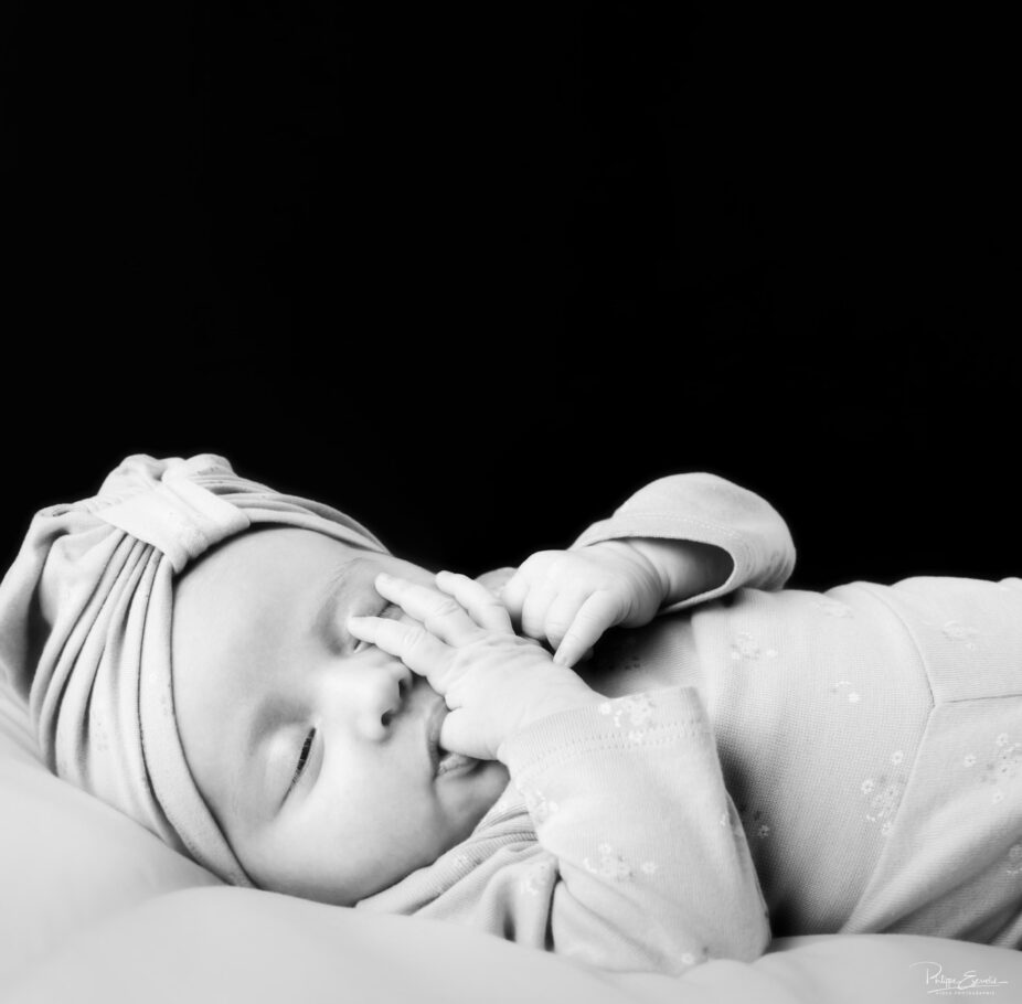 photo noir et blanc d'un bébé qui suce son pouce avec un turban sur la tête