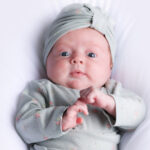 Un bébé portant un turban repose sur une couverture blanche