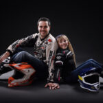 Portraits en studio fond gris d'un papa assis en tenue de motard et de sa fille habillée en motarde