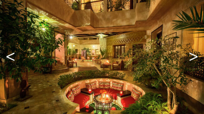 Patio d'un Riad de nuit avec un salon circulaire et des alcoves
