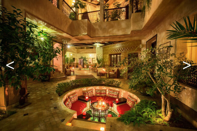 Patio d'un Riad de nuit avec un salon circulaire et des alcoves