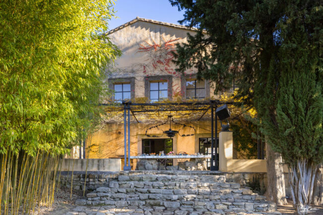Table en pierre dressée pour le petit-déjeuner sous une pergola ombragée, avec vue sur un jardin luxuriant