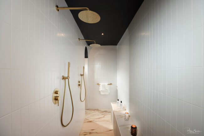 Douche double haut de gamme avec robinetterie dorée dans une love room à l’ambiance luxueuse