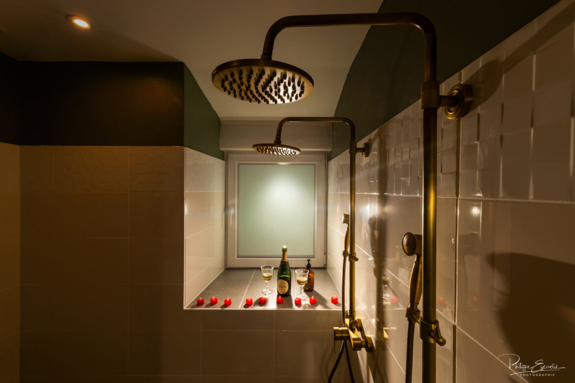 Douche double avec robinetterie dorée, bougies et champagne pour une ambiance sensuelle