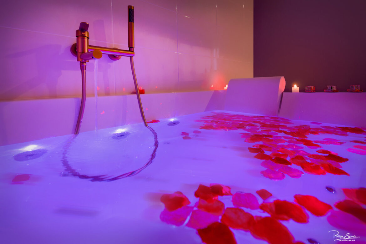 Jacuzzi romantique avec pétales de rose et éclairage tamisé violet