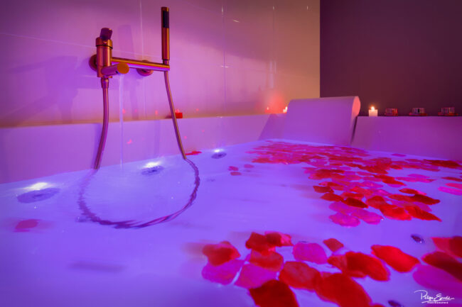 Jacuzzi romantique avec pétales de rose et éclairage tamisé violet