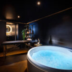 Espace bien-être avec jacuzzi, table de massage et ambiance tamisée dans une love room à Carcassonne