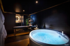 Espace bien-être avec jacuzzi, table de massage et ambiance tamisée dans une love room à Carcassonne