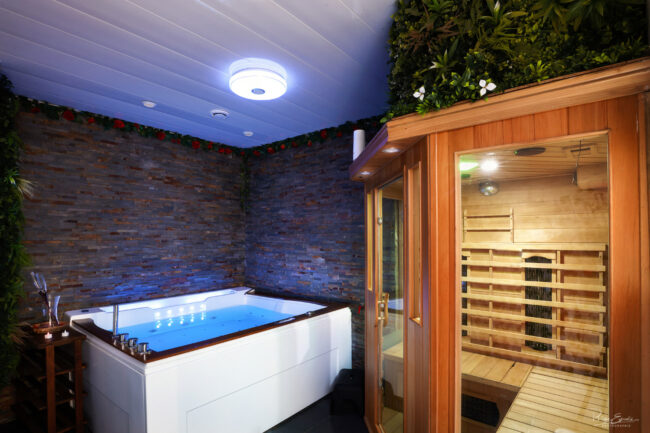 Espace bien-être avec jacuzzi et sauna en bois dans une love room à Carcassonne