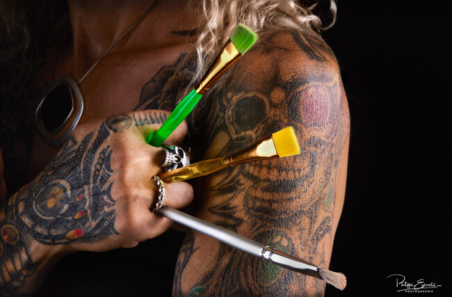 Photographe Portrait : Focus sur Cristelle Bernardinello, artiste peintre 6 Photo artistique en studio d’un bras tatoué tenant des pinceaux de peinture