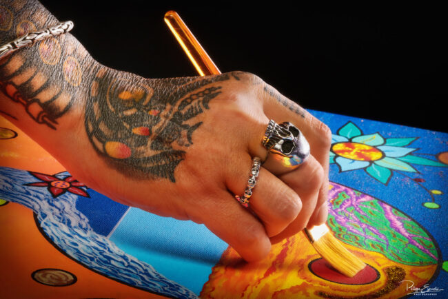 Photographe Portrait : Focus sur Cristelle Bernardinello, artiste peintre 4 Gros plan artistique sur une main tatouée tenant un pinceau en train de peindre une toile colorée