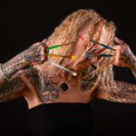 Photo artistique en studio d’une femme tatouée avec des pinceaux devant le visage – portrait par photographe à Carcassonne
