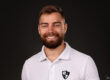 portrait de face d'un jeune homme barbu souriant