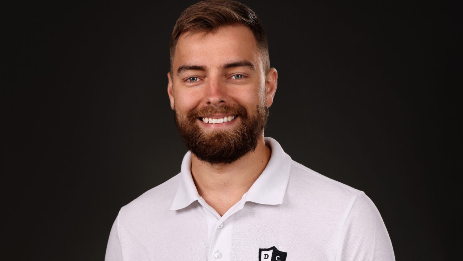 portrait de face d'un jeune homme barbu souriant