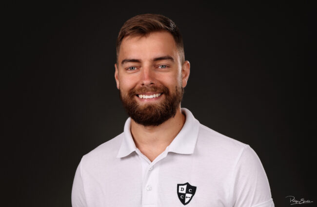 portrait de face d'un jeune homme barbu souriant