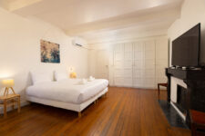 Chambre spacieuse avec lit double, grande télévision murale, sol en bois vernis et rangements intégrés