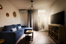 Salon cosy d’un studio à Carcassonne avec un grand canapé bleu et une télévision en face