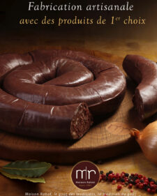 Boudin noir artisanal présenté en spirale sur une planche en bois avec oignon et épices