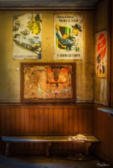 Salle d’attente de gare abandonnée avec banc en bois et vieilles affiches au mur