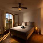 Chambre lumineuse avec lit double, miroir en pied et balcon donnant sur l’extérieur